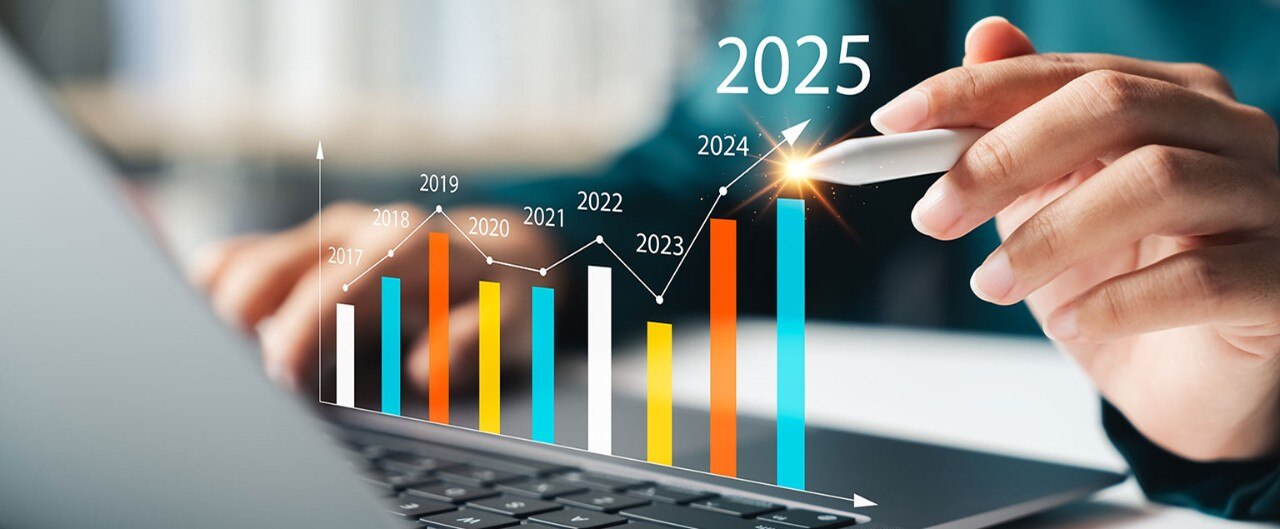 A person's hands using a laptop with an upward trending year-over-year financial graph