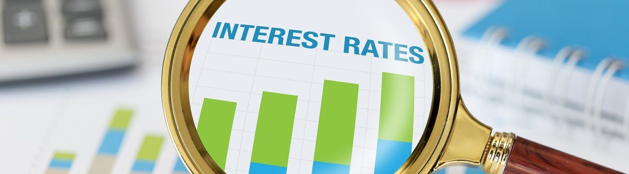 Magnifying glass and calculator on chart displaying increasing interest rates