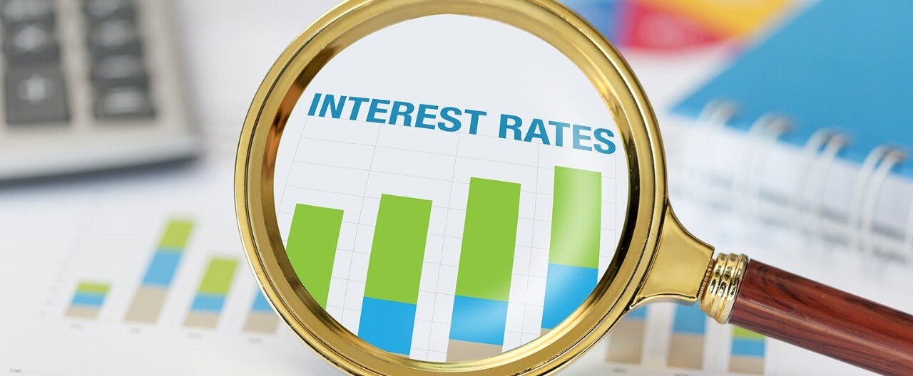 Magnifying glass and calculator on chart displaying increasing interest rates