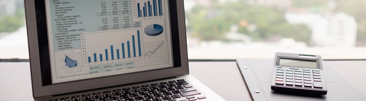 Open laptop displaying financial data, next to calculator