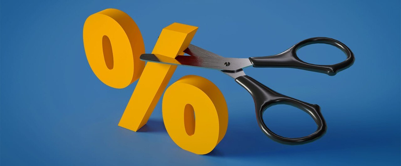 A pair of scissors cutting a yellow percentage sign