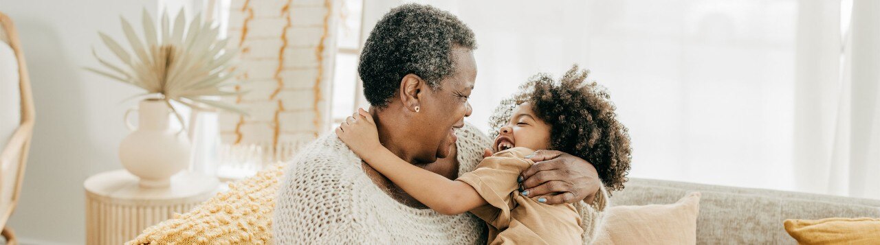 African-American grandmother hugging her granddaughter on a sofa