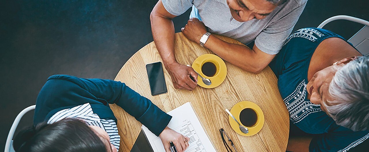 Couple sitting at small round table with advisor