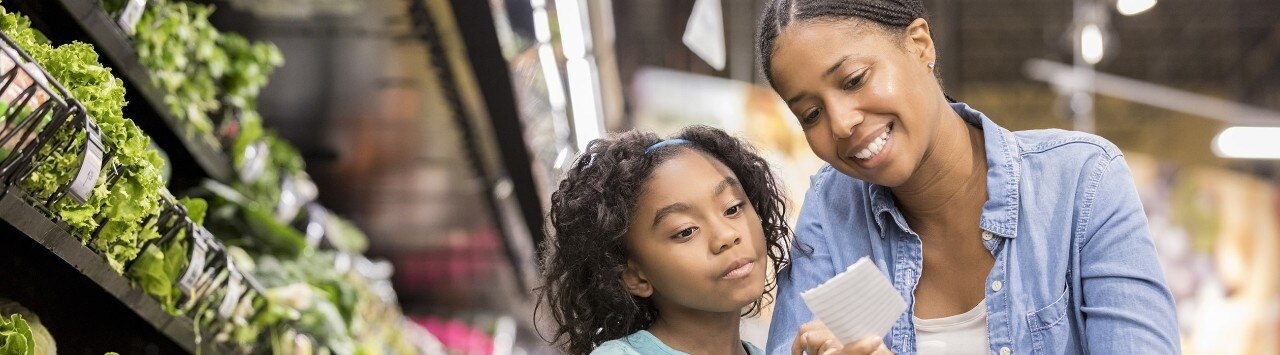African-American mother and daughter grocery shopping in produce aisle