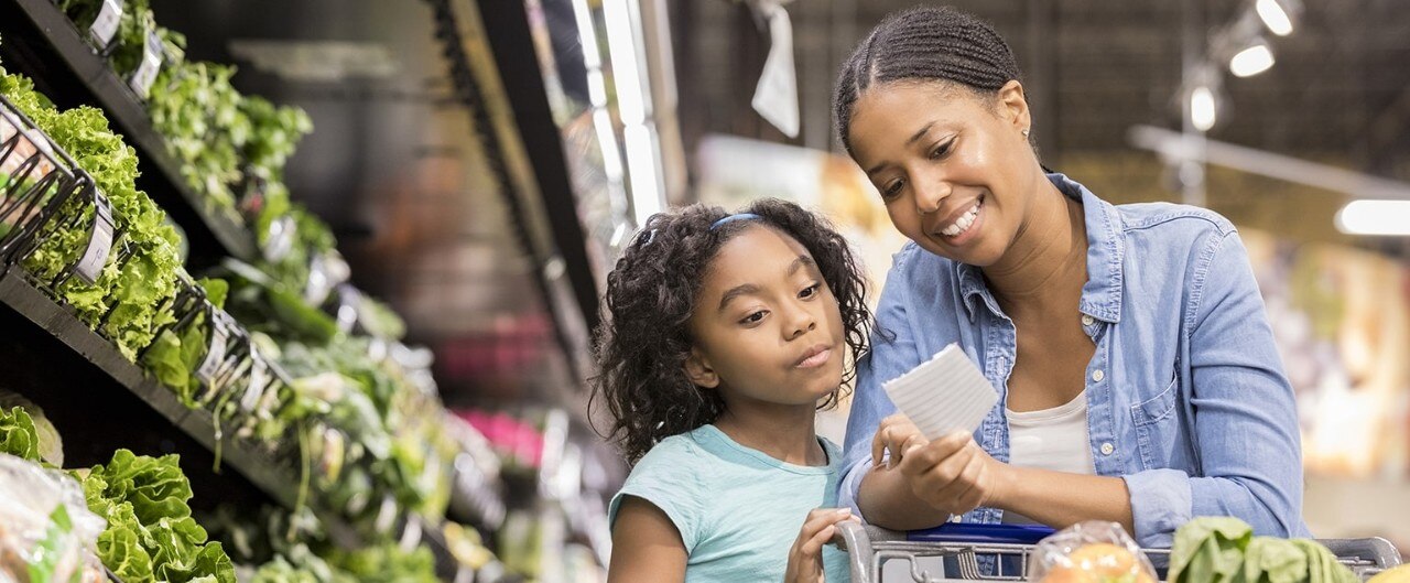 African-American mother and daughter grocery shopping in produce aisle