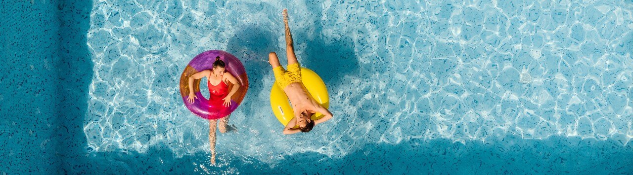 Overhead view of young Caucasian couple relaxing in rafts in swimming pool