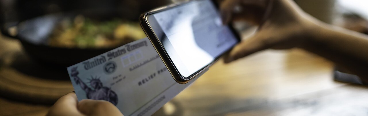 Person making mobile stimulus check deposit on smartphone