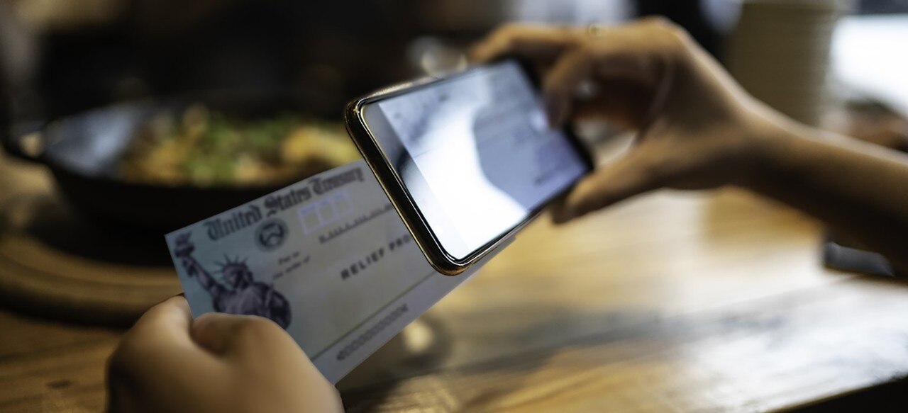 Person making mobile stimulus check deposit on smartphone